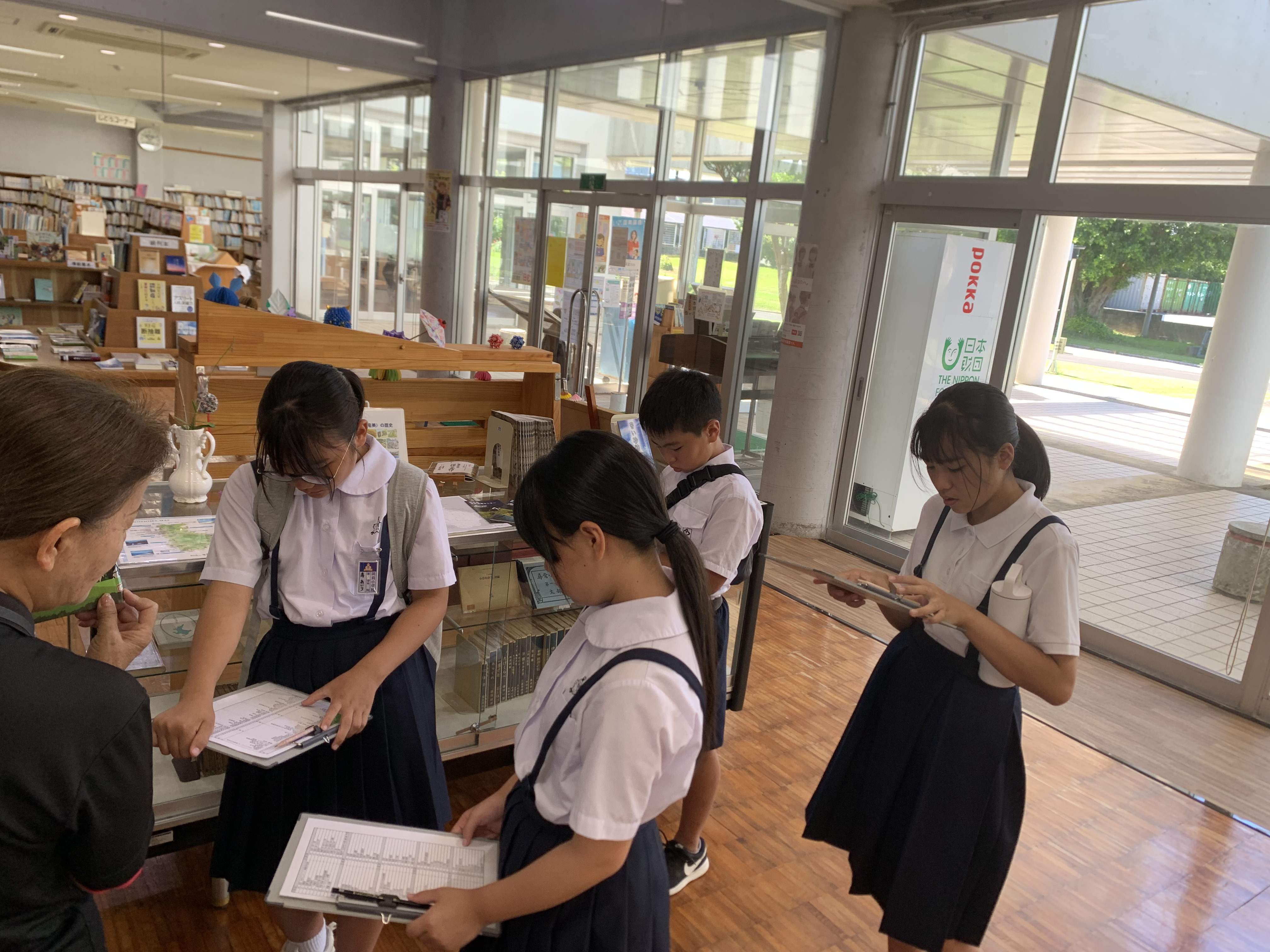 館長から分類ラベルについて説明を受けている生徒たち